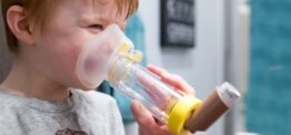 Child using asthma inhaler with spacer